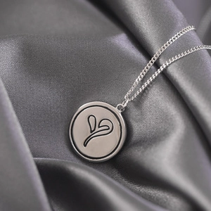 Macro shot of silver S925 necklace with round pendant on silk background