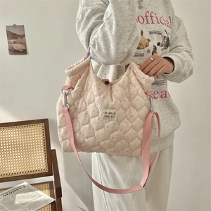 Detail of pink quilted tote bag with floral pattern and adjustable shoulder strap