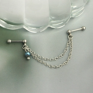 Detail of silver industrial piercing with double chains and blue faceted crystal bead