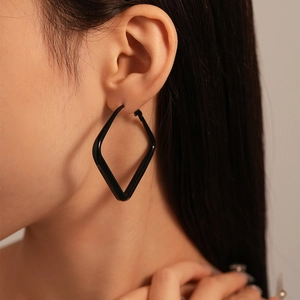Close-up of minimalist black geometric square hoop earrings worn by a female model