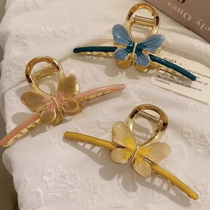 Three gradient butterfly metal hair claws set on soft white textured background