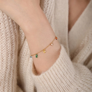 Elegant gold choker necklace with colorful zircon pendants worn on wrist for a layered look