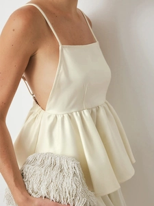 Off-white satin sleeveless top with open back, thin straps and ruffled peplum hem