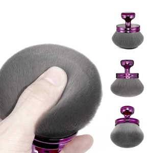 Close-up of a large purple powder brush with soft grey bristles for makeup or nail dust