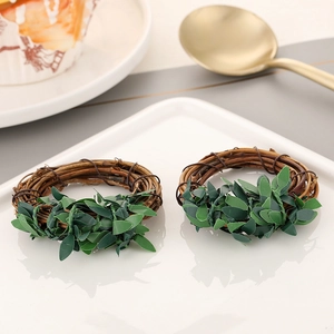 Detail view of woven brown rattan napkin rings with green leaves on white plates