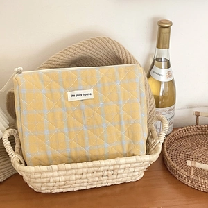 Quilted yellow checkered makeup bag in a woven basket with a vintage aesthetic look