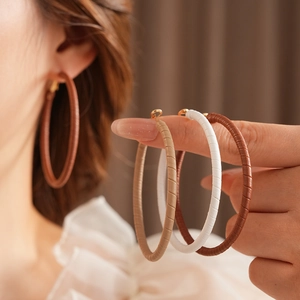 Detailed view of woven texture geometric hoop earrings in brown and white leather
