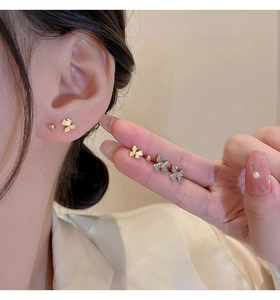 Detailed view of mini golden bow stud earrings with sparkling crystal accents on a model