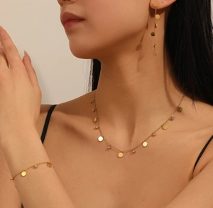 Detail of 18k gold plated stainless steel jewelry set with round coin pendants and zircons
