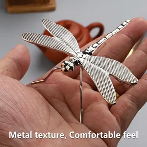 Macro detail of a silver metal dragonfly lid holder for Gongfu tea sets on palm
