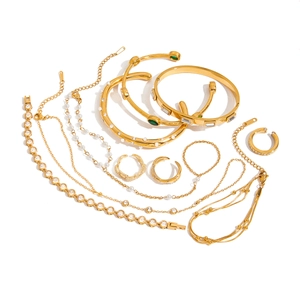 Ensemble de bijoux dorés avec colliers, bagues et bracelets en acier sur fond blanc
