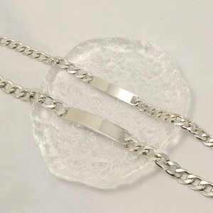 Polished titanium steel chain ID bracelets for couples on textured glass surface