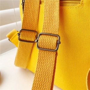 Detail of adjustable metal buckle and stitching on yellow canvas toddler backpack strap