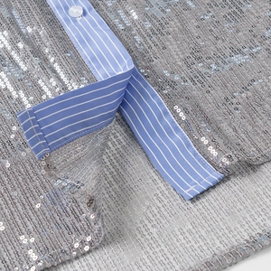 Détail de paillettes argentées sur tissu rayé avec coutures sur une chemise ajustée
