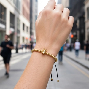 Detail of adjustable golden crown bracelet with blue gemstone on a model's wrist
