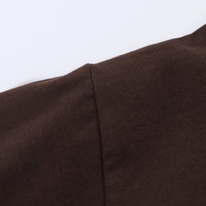Detailed macro view of high-quality shoulder stitching on dark brown knit dress fabric