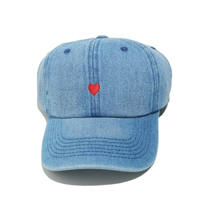 Close-up of the red heart embroidery on the front of a light blue denim baseball cap