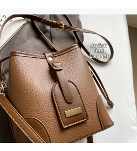 Detail of caramel brown litchi grain leather bucket bag with gold metal plaque and buckle