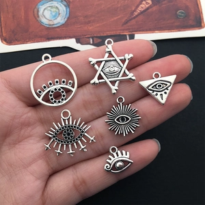 Set of six silver Eye of Horus alloy pendants displayed in hand for jewelry making