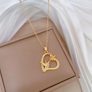 Close-up of golden heart pendant with crystal hummingbird and flower details on silk