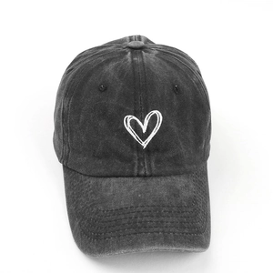 Detail of white heart embroidery on washed black cotton vintage baseball cap
