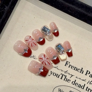 Détail de faux ongles œil-de-chat rouges avec dégradé français et strass brillants