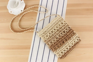 Detail of hand-woven straw crossbody bag with openwork pattern on a rustic wooden table