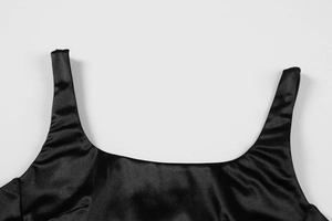 Detailed close-up of the square neckline and glossy satin fabric of the black midi dress
