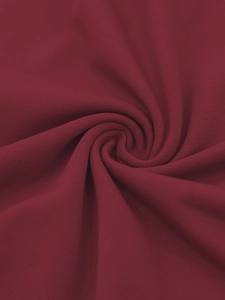 Vue macro du tissu tricoté bordeaux doux montrant la texture fine et la qualité du drapé