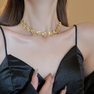 Close-up of elegant gold flower necklace worn by a model on a minimalist black top