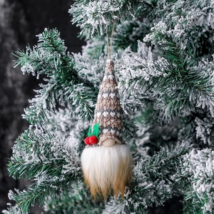 Christmas gnome ornament with beige knit hat and plush beard on snowy tree branch