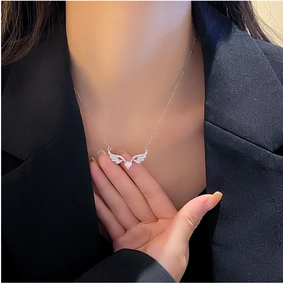 Detailed view of angel wing necklace with heart zircon pendant worn on a model