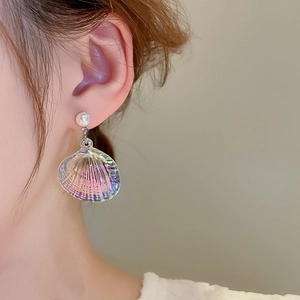 Macro shot of shell pendant earrings with shimmering pearl stud on a model's ear