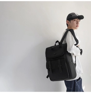 Side view of black nylon backpack with flap and buckle straps worn by a model