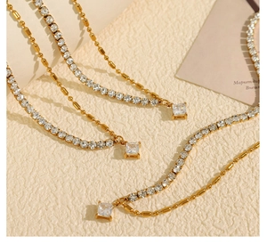 Détail de chaînes tennis dorées avec pendentifs carrés en cristal sur surface beige