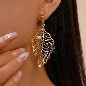 Golden hollow leaf drop earrings with white pearl and black enamel butterfly on model