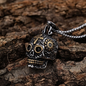 Gothic stainless steel sugar skull pendant with gold cross on rustic wood background