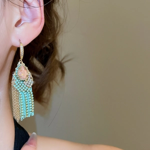 Detail of vintage boho long fringe earrings with mint green beads and golden tassels