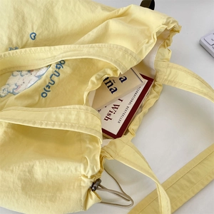 Close-up of lemon yellow embroidered canvas tote bag showing large capacity for books