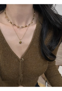 Close-up of a layered gold necklace with tiger eye pendant on a female model