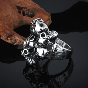 Macro shot of silver vintage skull rings on black mirror with rustic wood accent