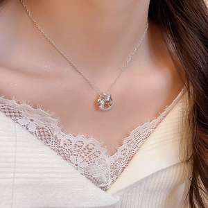 Close-up of silver rocking horse pendant necklace worn with white lace top for women