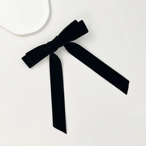 Detailed view of the soft black velvet fabric texture on a long streamer bow hair clip