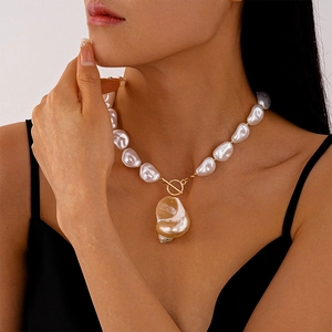 Close-up of baroque pearl necklace with natural conch shell pendant and golden T-bar clasp