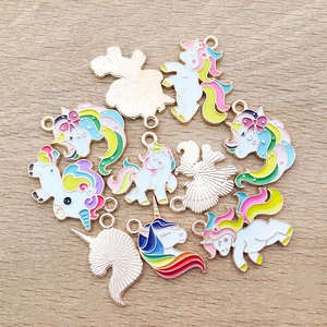 Detail of colorful unicorn enamel charms with gold plating on a wooden surface