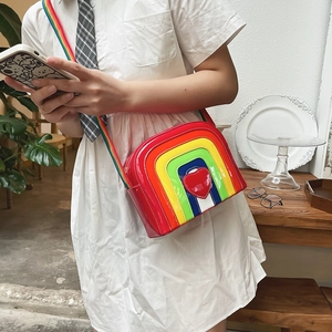 Detail of a rainbow crossbody bag with a 3D red heart and shiny leather texture
