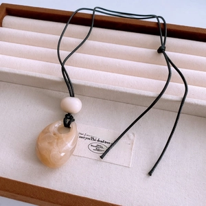 Detailed macro view of the amber resin water drop pendant on a minimalist black wax cord