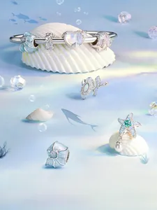 Detailed view of silver sea shell and starfish charms on a beaded ocean style bracelet