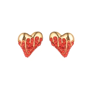 Vintage heart earrings with melting gold metal design and red zircons on white background