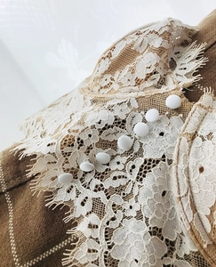 Detail of floral lace trim with fabric buttons on brown plaid lace back lingerie